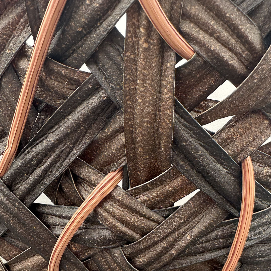 Closeup of cone basket with two thicker different brown bands making up most of the basket with lighter thinner brown bands interlocking 