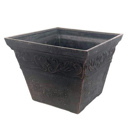 Square black pot brushed with copper with ornate pattern at top 