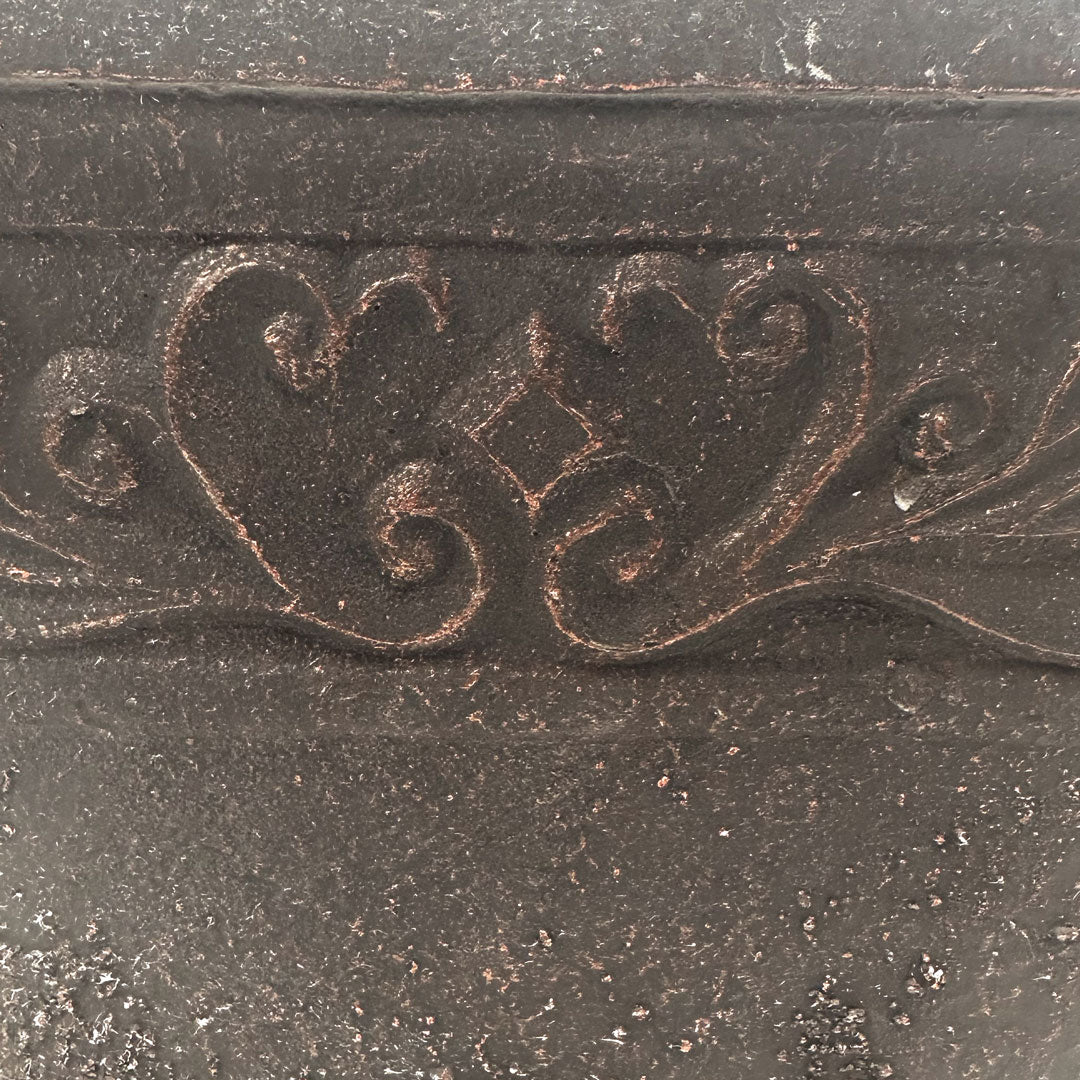 Closeup of black pot with copper brushed of ornate pattern