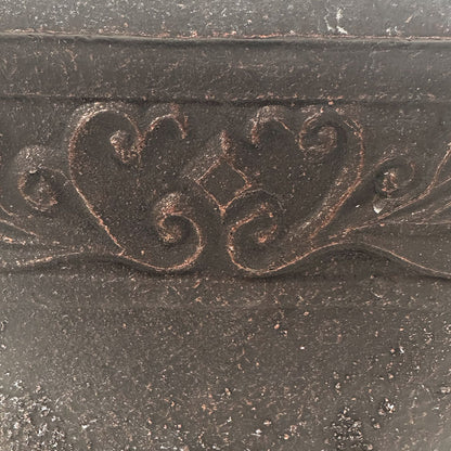 Closeup of black pot with copper brushed of ornate pattern