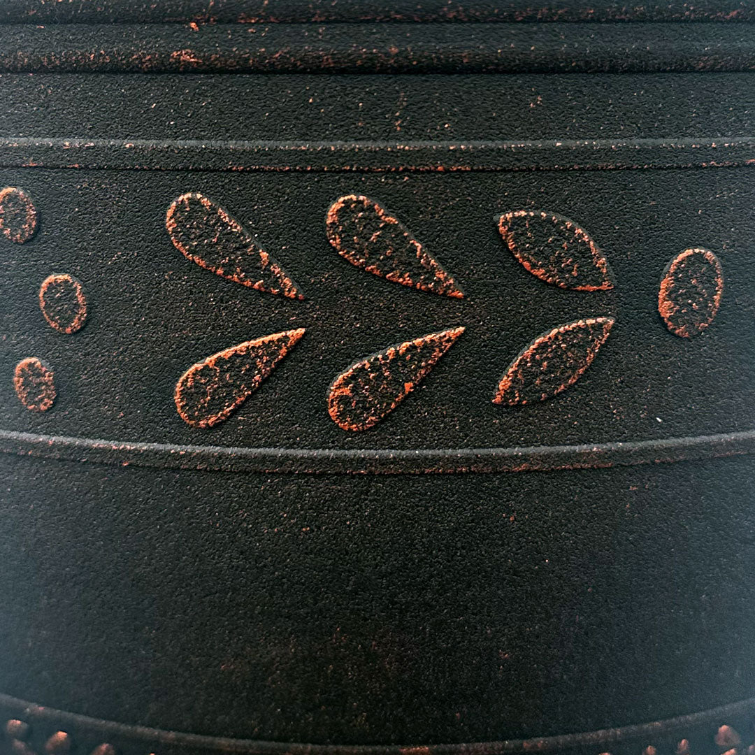 Close up of black pot with Brushed Copper band pattern that is an abstract flower and leaf pattern